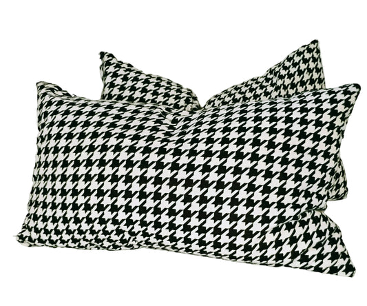 Two black and white houndstooth patterned pillows on a white surface.